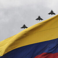 Kfir aircraft of the Colombian Air Force overfly a Colombian flag during a ceremony commemorating Colombia's Independence Day in Bogota on July 20, 2021. (Photo by Juan BARRETO / AFP)