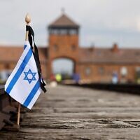 A small Israeli flag on the rail tracks at the site of the former Auschwitz-Birkenau camp during commemorations to honor the victims of the Holocaust, near the historical gate of Birkenau (Auschwitz II) near the village of Brzezinka near Oswiecim, Poland on April 28, 2022. (Wojtek Radwanski / AFP)