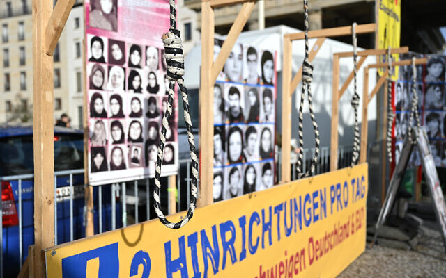 Các bức chân dung được trưng bày sau một chiếc thòng lọng khi tấm bảng ghi 'Ngày hành quyết chuyên nghiệp' trước Cổng Brandenburg trong cuộc biểu tình của những người ủng hộ Hội đồng Kháng chiến Quốc gia Iran ở Berlin, Đức vào ngày 10 tháng 2 năm 2024. (Stefanie Loos/AFP)