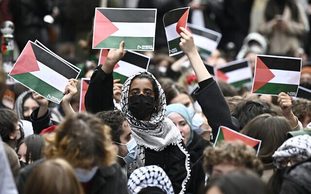 Protesters hold posters of the Palestinian flag as they demonstrate near the entrance of the Institute of Political Studies, Sciences Po Paris, occupied by students, in Paris, France on April 26, 2024. (Julien De Rosa / AFP)