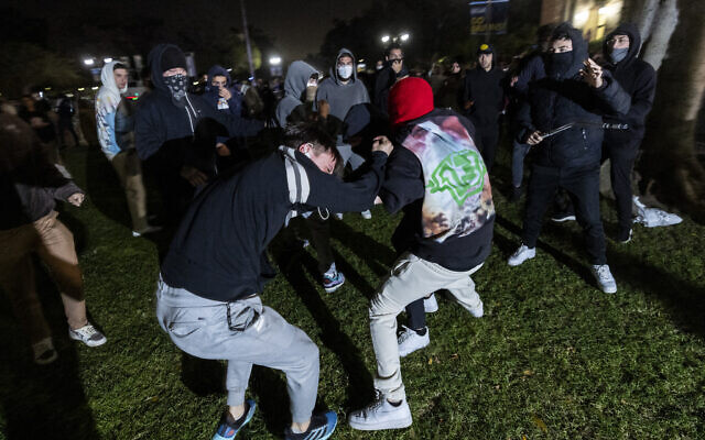 A pro-Palestinian demonstrator is beaten by counter-protesters attacking the anti-Israel encampment set up on the campus of the University of California Los Angeles (UCLA) as clashes erupt, in Los Angeles on May 1, 2024. (Etienne Laurent/AFP)