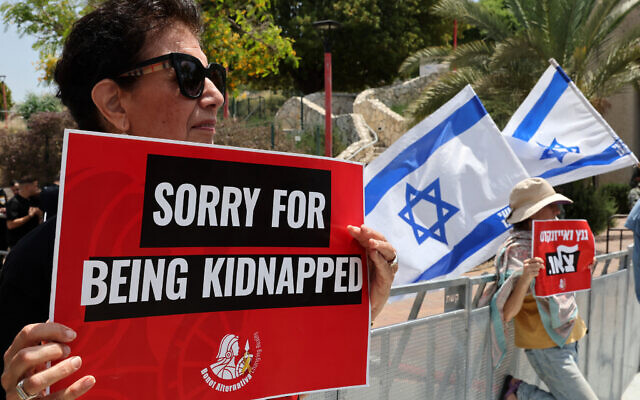 A woman holds a placard during a rally near the house of war cabinet minister Benny Gantz in the central town of Rosh Ha'ayin, on May 3, 2024, calling on the government to reach an agreement for the release of all hostages held by terror groups in Gaza since October 7. (Jack Guez/AFP)
