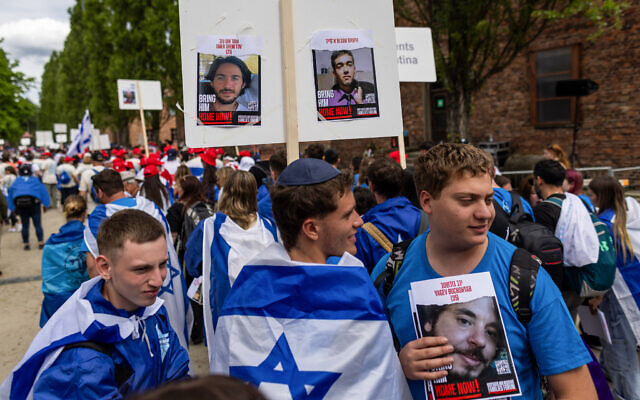 Participants display placards reading "Bring him Home" and showing pictures of hostages held by terrorists in Gaza at the annual March of The Living to honor the victims of the Holocaust at the Memorial and Museum Auschwitz-Birkenau on the site of the Auschwitz concentration camp in Oswiecim, Poland, on May 6, 2024 (Wojtek Radwanski / AFP)