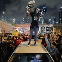 Einav Zangauker holds a sign identifying her son Matan (24), one of the hostages taken captive by Hamas in the Gaza Strip during the October 7 massacre, as she stands on the roof of a car during a demonstration by hostages' relatives and supporters in Tel Aviv on May 6, 2024. (Jack Guez / AFP)