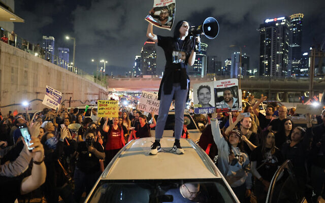 Einav Zangauker holds a sign identifying her son Matan (24), one of the hostages taken captive by Hamas in the Gaza Strip during the October 7 massacre, as she stands on the roof of a car during a demonstration by hostages' relatives and supporters in Tel Aviv on May 6, 2024. (Jack Guez / AFP)