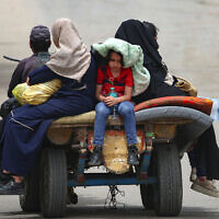 Palestinians sit on a cart as they move to safer areas in Rafah, in the southern Gaza Strip, on May 10, 2024. (AFP)