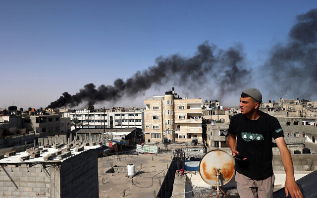 A man looks on as thick, black smoke rises from a fire in a building in Rafah in the southern Gaza Strip on May 10, 2024. (Photo by AFP)
