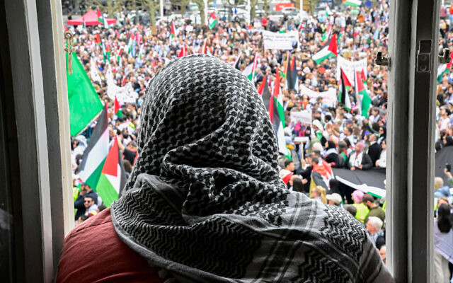 A man wearing a keffiyeh looks out of a window as anti-Israel protesters demonstrate in Malmo, Sweden, on May 11, 2024 (Tobias SCHWARZ / AFP)