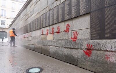 A city employee cleaning the "Wall of the Righteous" (Mur des Justes) after the monument was vandalized in Paris, May 14, 2024. (Antonin Utz/AFP)