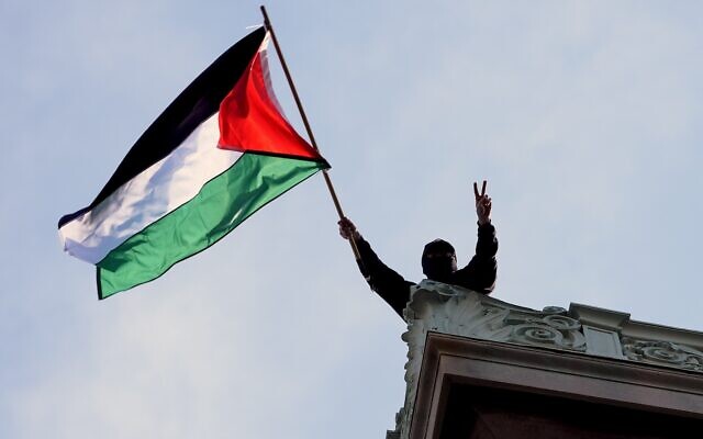 A student protester waves a Palestinian flag above Hamilton Hall on the campus of Columbia University, Tuesday, April 30, 2024, in New York. (Pool Photo/Mary Altaffer)