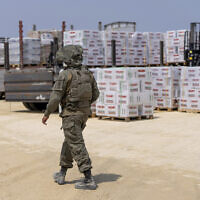 An Israeli soldier walks through an inspection area for trucks carrying humanitarian aid supplies bound for the Gaza Strip, on the Palestinian side of the Erez crossing from southern Israel, Wednesday, May 1, 2024. (AP Photo/Ohad Zwigenberg)