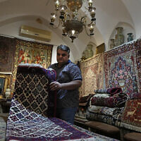 Iranian carpet shop owner Ali Faez works at his shop at the traditional bazaar of the city of Kashan, about 152 miles (245 km) south of the capital Tehran, Iran, April 30, 2024. (AP Photo/Vahid Salemi)