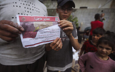 Palestinians hold leaflets dropped by Israeli planes calling on them to evacuate ahead of an Israeli military operation in Rafah, southern Gaza Strip, May 6, 2024. (AP Photo/Ismael Abu Dayyah)