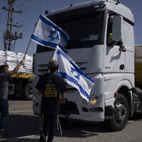 People holding Israeli flags stand in front of trucks carrying humanitarian aid as they try to stop them from entering the Gaza Strip near the Kerem Shalom border crossing, May 9, 2024. (AP Photo/Leo Correa)