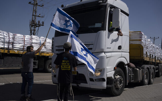 File - People holding Israeli flags stand in front of trucks carrying humanitarian aid as they try to stop them from entering the Gaza Strip near the Kerem Shalom border crossing, May 9, 2024. (AP Photo/Leo Correa)