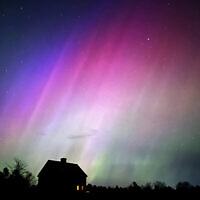 The northern lights flare in the sky over a farmhouse, May 10, 2024, in Brunswick, Maine. (AP Photo/Robert F. Bukaty)