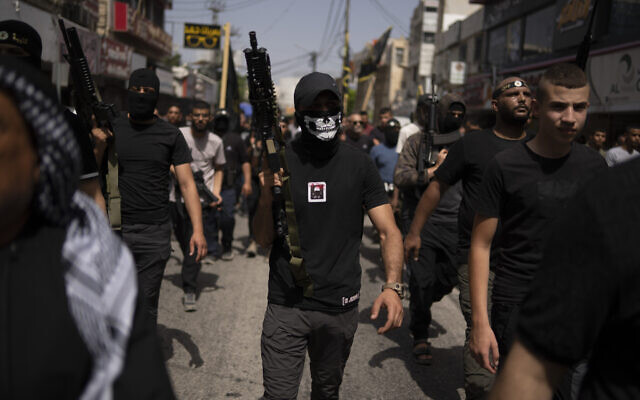 Gunmen march as mourners carry the bodies of Palestinians, some draped in Islamic Jihad terrorist group flags, during their funeral in the West Bank city of Jenin, May 23, 2024. (AP Photo/Leo Correa)