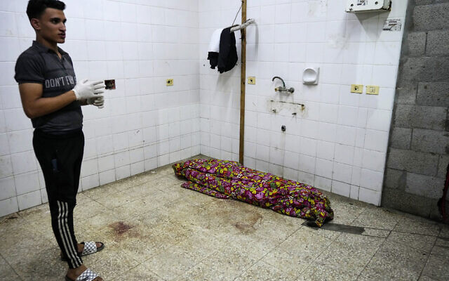 A Palestinian medic stands near a body at the morgue of Al Aqsa hospital in Deir al Balah, central Gaza Strip, on May 26, 2024. (AP Photo/Abdel Kareem Hana)