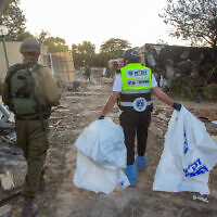 ZAKA volunteers walk through the destruction caused by Hamas terrorists in Kibbutz Kfar Aza, as they collect dead bodies, October 15, 2023. (Edi Israel/ Flash90)