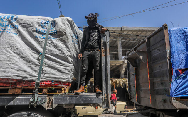 Armed and masked Palestinians seen on trucks loaded with international humanitarian aid entering Gaza via the Israeli Kerem Shalom Crossing, southern Gaza Strip, April 3, 2024. (Abed Rahim Khatib/Flash90