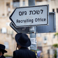 Ultra-Orthodox Jewish men near a sign reading 'army recruitment office' during a protest against the drafting of Haredim to the military, in Jerusalem, May 1, 2024. (Yonatan Sindel/Flash90)