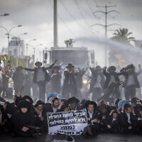 Ultra-Orthodox demonstrators block a road and clash with police during a protest against the Haredi draft, on Route 4, outside the city of Bnei Brak, May 2, 2024. (Chaim Goldberg/Flash90)