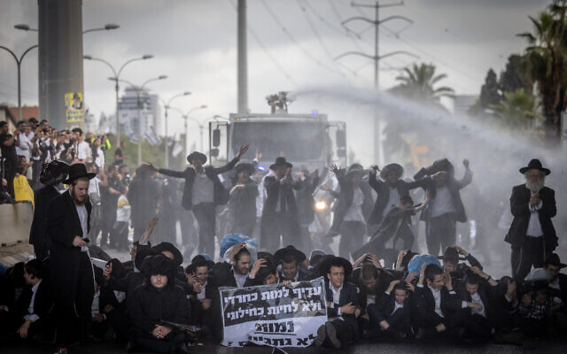 Ultra-Orthodox demonstrators block a road and clash with police during a protest against the Haredi draft, on Route 4, outside the city of Bnei Brak, May 2, 2024. (Chaim Goldberg/Flash90)