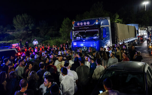 Israeli security forces guard aid trucks making their way to the Gaza Strip while people protest them, on Route 1 between Jerusalem and Tel Aviv, May 6, 2024. (Chaim Goldberg/Flash90)