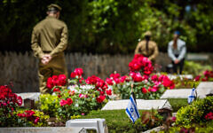 Israeli soldiers place flags on graves of soldiers during a  ceremony at the Mount Herzl military cemetery in Jerusalem, May 8, 2024. (Yonatan Sindel/Flash90)