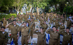 Soldiers and members of security forces who treated and cared for Israeli soldiers killed on and since the Hamas invasion on October 7 place flags and light candles on soldiers' graves at Mount Herzl Military Cemetery in Jerusalem, on May 9, 2024, days before the annual Memorial Day for Israel's Fallen Soldiers. (Chaim Goldberg/Flash90)