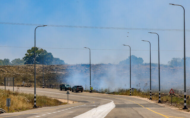 Smoke rises from the side of a road after rockets fired from Lebanon hit an open area in the Golan Heights, May 16, 2024. (David Cohen/Flash90)