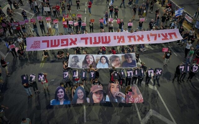 Illustrative: Demonstrators hold images of five female soldiers held hostage by Hamas in Gaza, with a sign reading: 'Save those who can still be [saved],' outside the Defense Ministry in Tel Aviv, May 25, 2024. (Erik Marmor/Flash90)