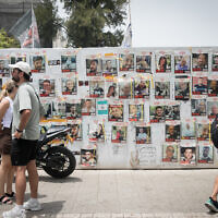 People in Tel Aviv walk by photographs of hostages held in Gaza, on May 28, 2024. (Miriam Alster/Flash90)