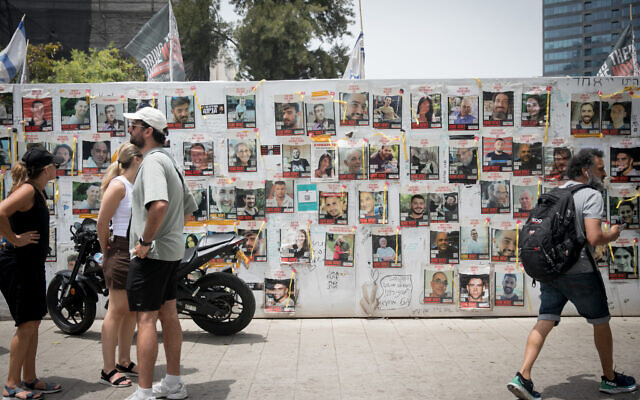 People in Tel Aviv walk by photographs of hostages held in Gaza, on May 28, 2024. (Miriam Alster/FLASH90)