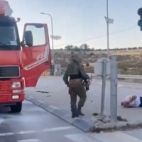 An IDF soldier (center) at the scene where far-right activists attacked a truck, leaving the driver (right) laying on the ground bloodied, Givat Asaf Junction, West Bank, May 15, 2024. (X screenshot)