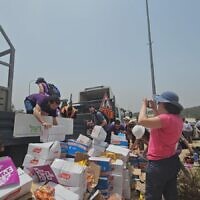 Activists from the Standing Together organization help reload cartons of humanitarian aid destined for Gaza thrown off a truck by extremists opposing the supply of aid to Gaza at the Tarqumiyah Crossing in the West Bank, May 19, 2024. (Courtesy Standing Together)