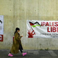 A student from the Public University of Navarra passes next to banners in Basque and Spanish supporting Palestinians and calling to "combat, denormalize and destroy Israel," in Pamplona, northern Spain, on Wednesday, April 8, 2024. (AP/Alvaro Barrientos)