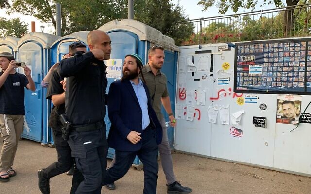 Religious Zionism MK Zvi Sukkot is escorted by police away from an anti-government protest taking place outside the Knesset in Jerusalem on May 20, 2024. (Charlie Summers/Times of Israel)