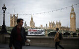 A banner reading "Keir Starmer: Will Labour Stop Arming Israel?" is hung over the side of Westminster Bridge, in front of the Palace of Westminster, in London on June 3, 2024. (Henry Nicholls/AFP)