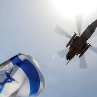 An Israel Air Force CH-53 Sea Stallion military helicopter flies over as people gather with Israeli national flags outside Sheba Tel Hashomer Medical Centre in Ramat Gan on June 8, 2024, where Israeli hostages were transferred after being rescued from captivity in the Gaza Strip since the October 7 attacks. (Jack Guez / AFP)