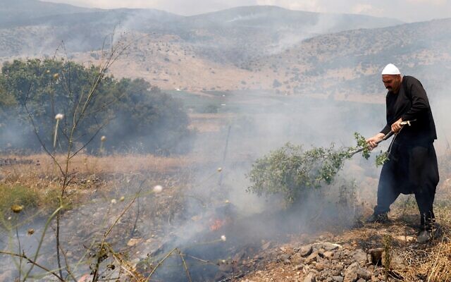A local Druze man tries to put out flames in a field after rockets launched from southern Lebanon landed on the Banias area in the Golan Heights on June 9, 2024. (Jalaa MAREY / AFP)