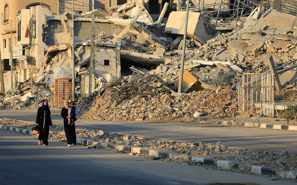 Palestinians walk past destroyed buildings in al-Bureij camp in the central Gaza Strip on June 12, 2024, amid the ongoing conflict between Israel and the Hamas terror group. (Photo by Eyad BABA / AFP)
