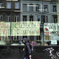 People walk by banners hanging inside a window of an an encampment set up by pro-Palestinian and anti-Israel students and activists at Ghent University, as students occupy parts of the campus in Ghent, Belgium, May 16, 2024. (AP Photo/Virginia Mayo)