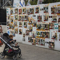 Passersby observe the photos of hostages held in the Gaza Strip that are plastered to the walls of a plaza known as Hostages Square in Tel Aviv, Israel, May 17, 2024 (AP Photo/Oded Balilty).