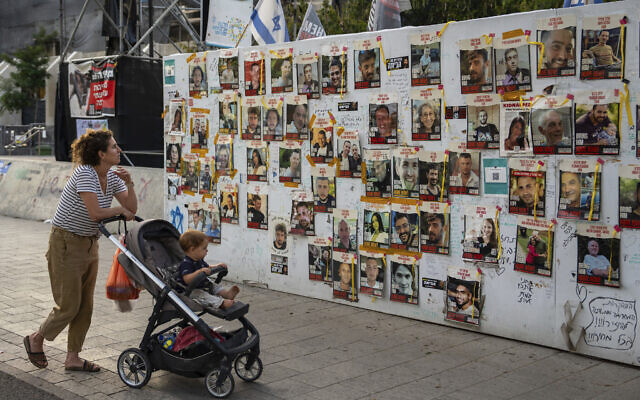 Passersby observe the photos of hostages held in the Gaza Strip that are plastered to the walls of a plaza known as Hostages Square in Tel Aviv, Israel, May 17, 2024 (AP Photo/Oded Balilty).