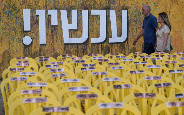 People walk past a large mural reading "Now" at  Hostage Square in Tel Aviv. June 2, 2024. (Avshalom Sassoni/Flash90)