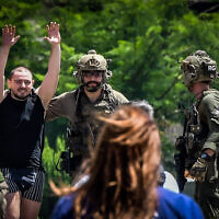 Rescued hostage Almog Meir Jan raises his hands in celebration as he is escorted from an IDF helicopter on arrival at Sheba Medical Center in Ramat Gan, June 8, 2024. (Avshalom Sassoni/Flash90)