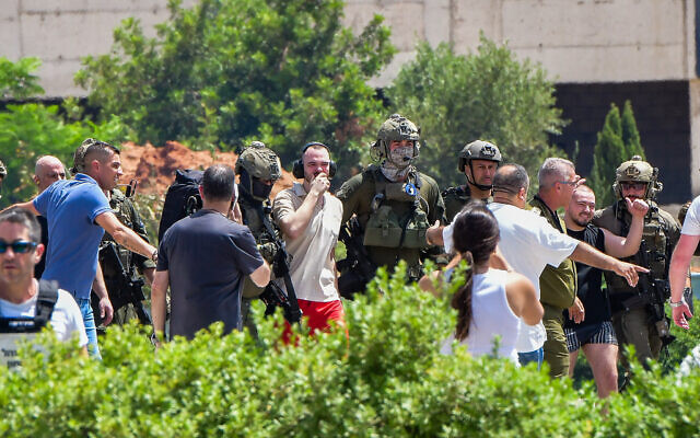 Rescued hostages Andrey Kozlov (white shirt) and Almog Meir Jan (black shirt), freed by the IDF from Hamas captivity in Gaza, are escorted from an IDF helicopter on arrival at the Sheba Medical Center in Ramat Gan, June 8, 2024. (Avshalom Sassoni/Flash90)