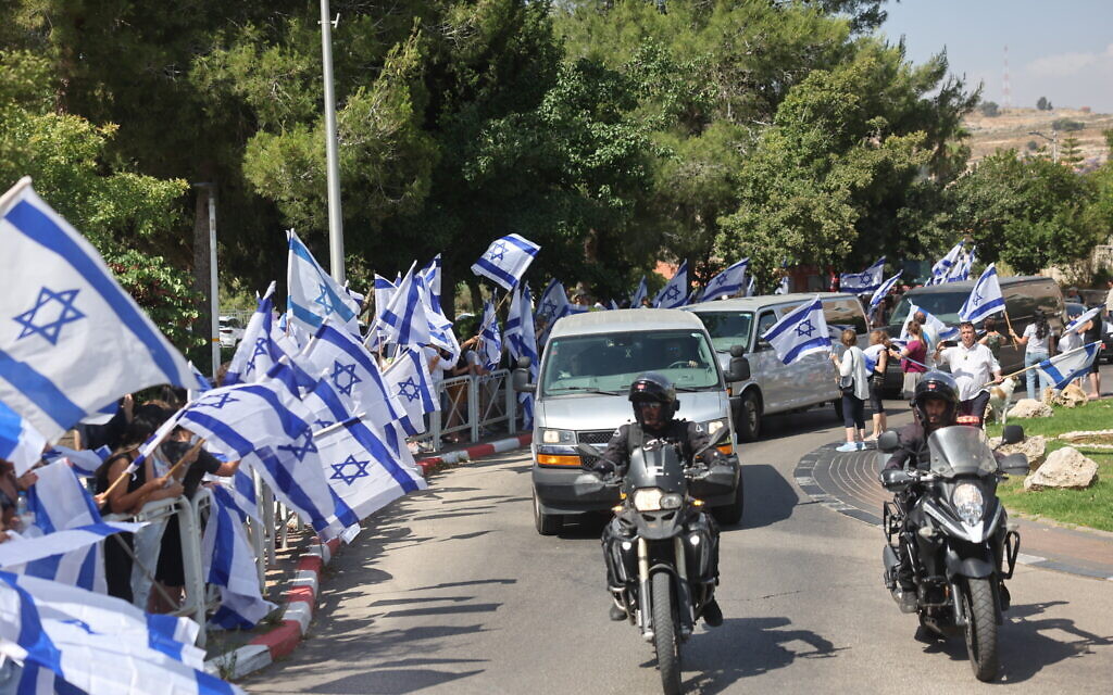 Israelis lining roads in Jerusalem wave flags on June 9, 2024, as they pay respects to the funeral procession for officer Arnon Zamora, who was killed in battle in a special forces operation in Gaza where four Israeli hostages were rescued a day earlier. (Yonatan Sindel/Flash90)