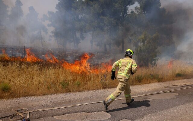 Firefighters work to extinguish a fire sparked by rockets launched from Lebanon, at the Biriya Forest in northern Israel, June 13, 2024. (David Cohen/Flash90)
